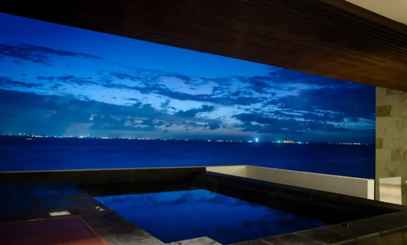 Alberca del penthouse de noche con skyline de Cancún